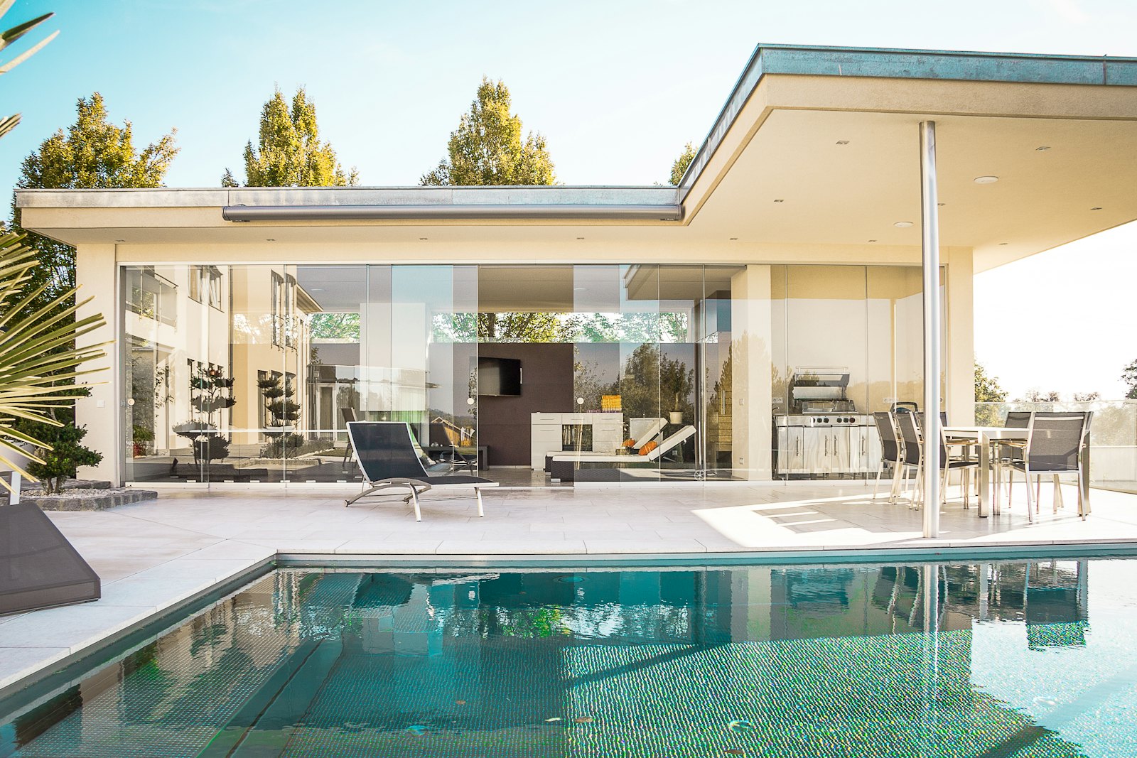 Pool-side home with walls of spotless glass reflecting the sky