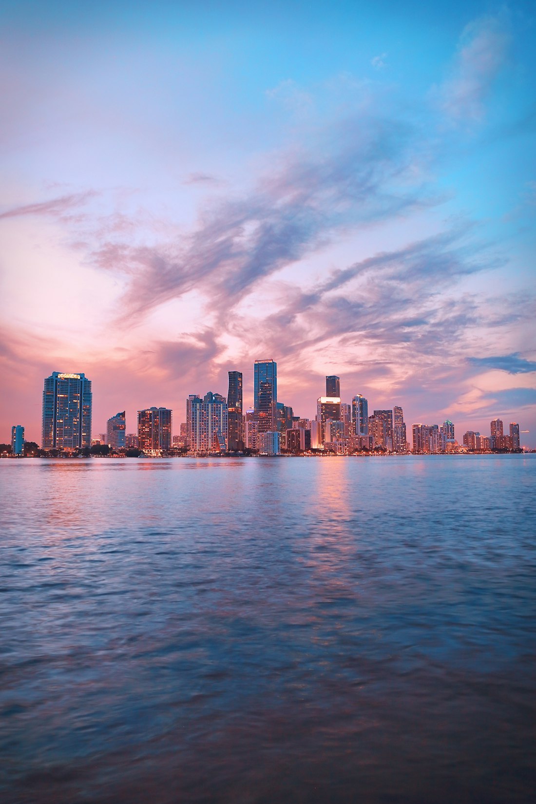 Miami skyline across Biscayne Bay under a pink and blue sunset sky