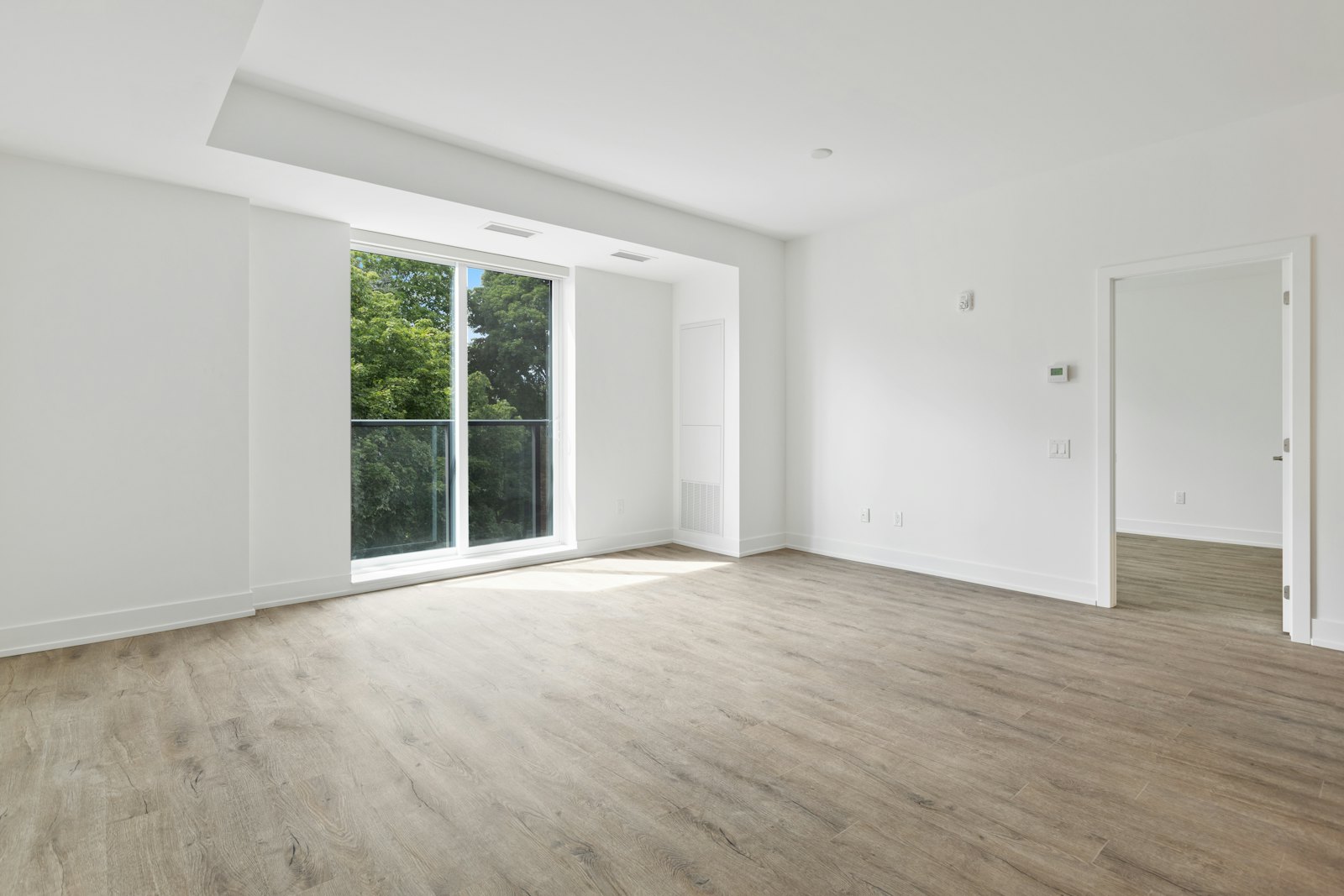 Sunlit empty room with a clean sliding glass door to a balcony