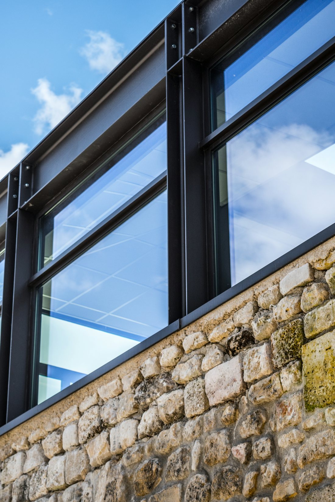 Exterior windows with dark frames reflecting blue sky above a stone sill